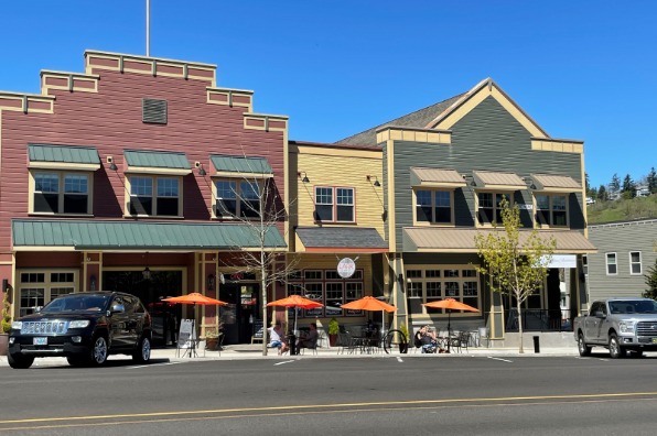 view from across the street of Main Street building exteriors and tables with orange umbrellas in front