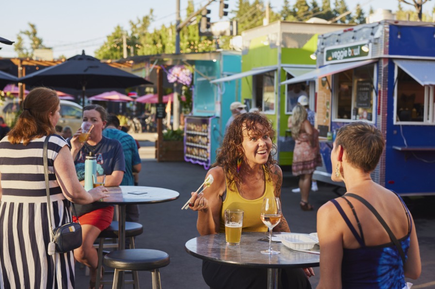 People eating at tables outside food carts in Oregon City