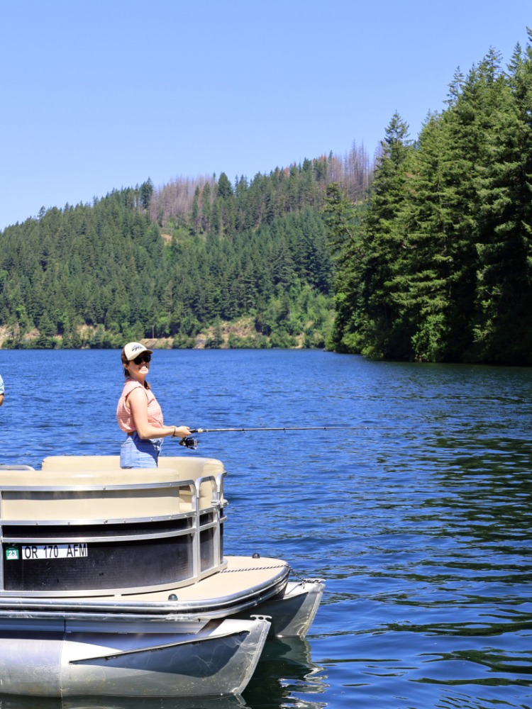 Angler casts fishing line into water from a pontoon boat with friends
