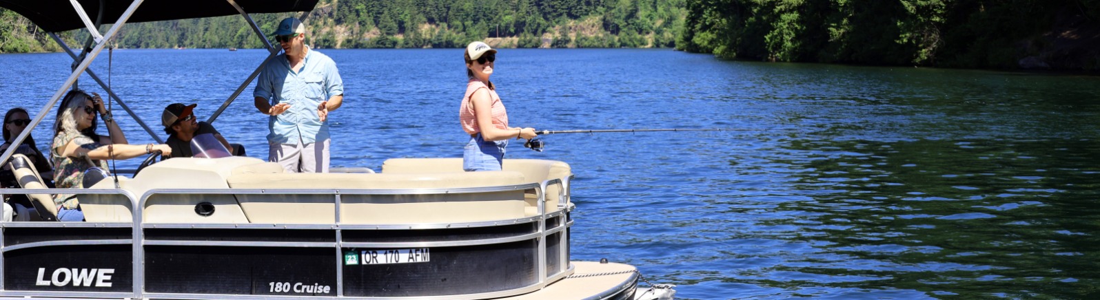 Angler casts fishing line into water from a pontoon boat with friends