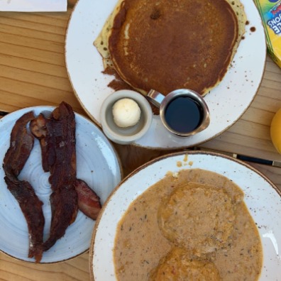 Pancakes, bacon, and biscuits and gravy brunch on a wooden table