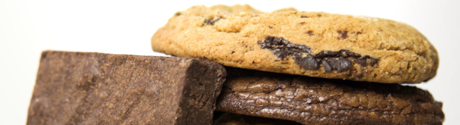 A single brownie leans against a stack of five cookies