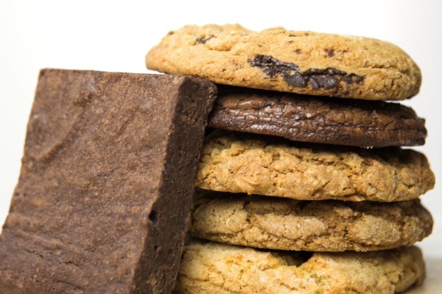 A single brownie leans against a stack of five cookies