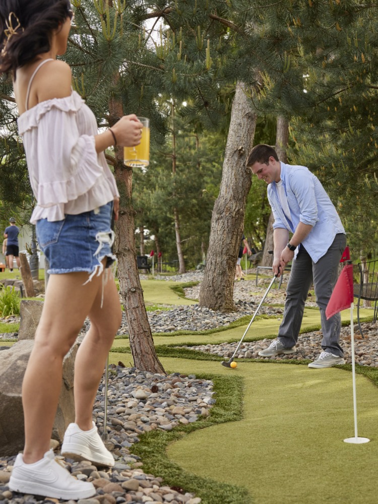 Three people play mini golf