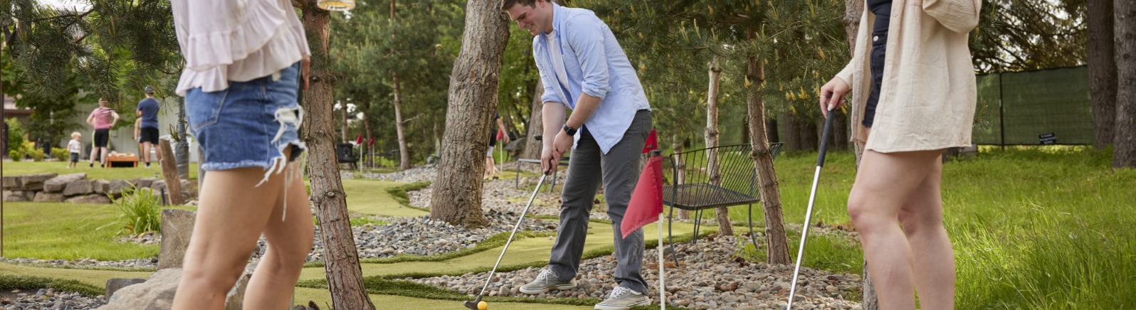 Three people play mini golf