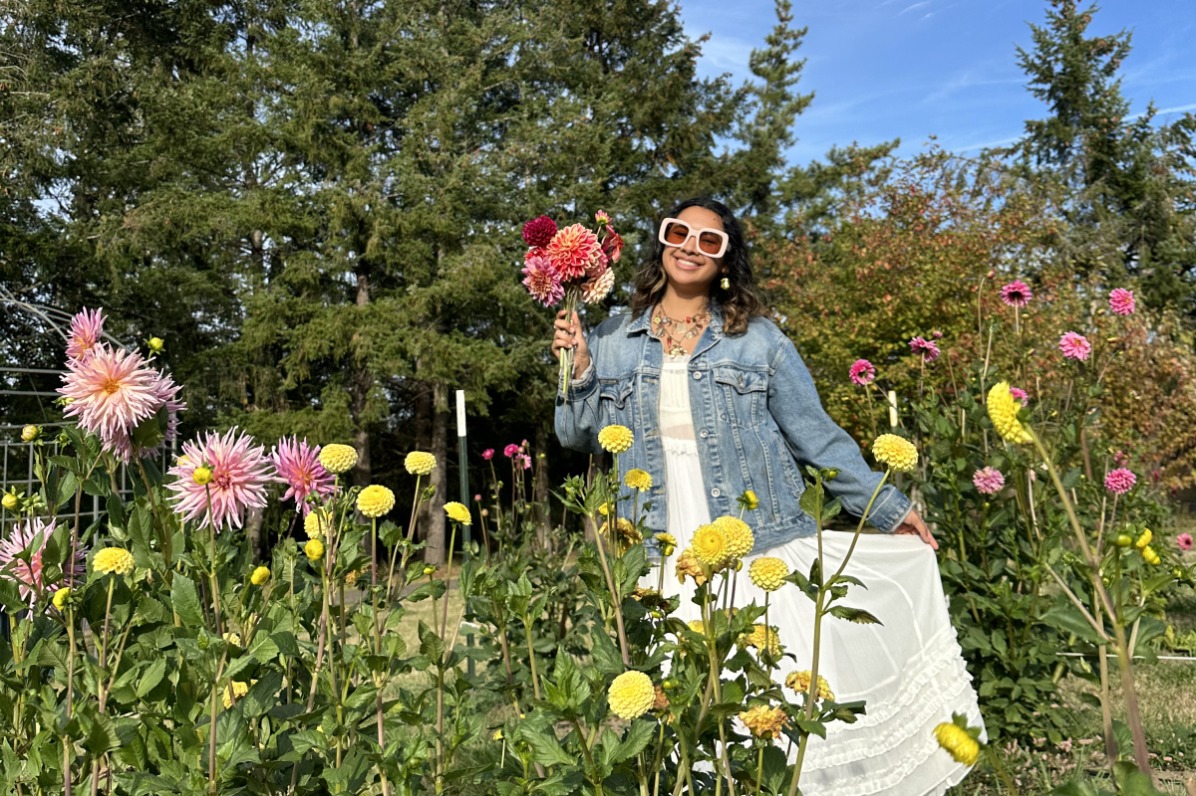 Person in a dress and sunglasses holds a bouquet in a dahlia field