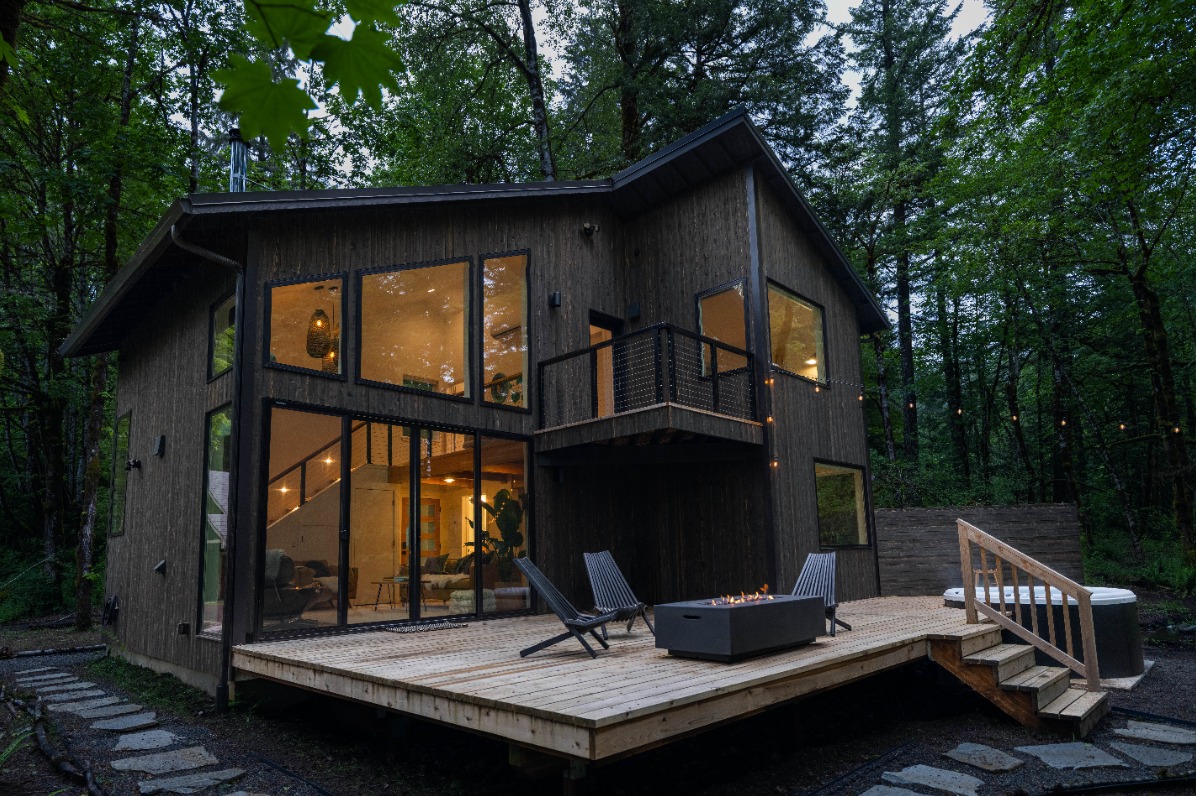 Midnight Hollow Cabin viewed from the back deck  has warm lighting glowing in the windows. 