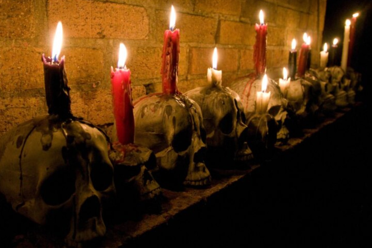 Lit pillar candles burn atop faux skulls at Davis Graveyard Halloween display.