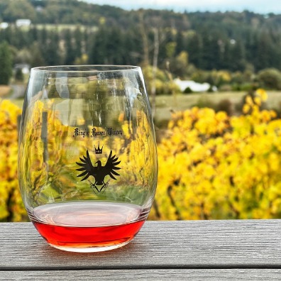 Glass of red wine with fields of grapes in fall yellow colors.