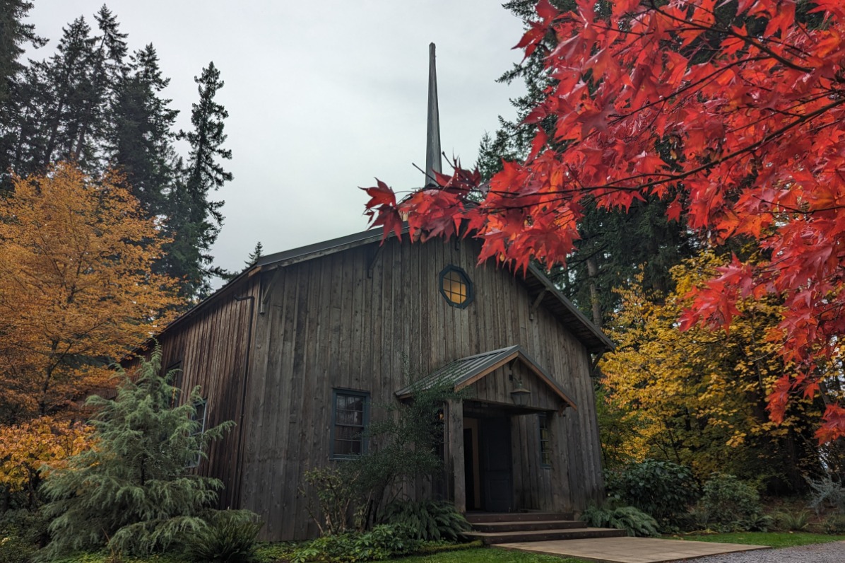 Camp Colton's wooden chapel with a spire is surrounded with colorful autumn trees.