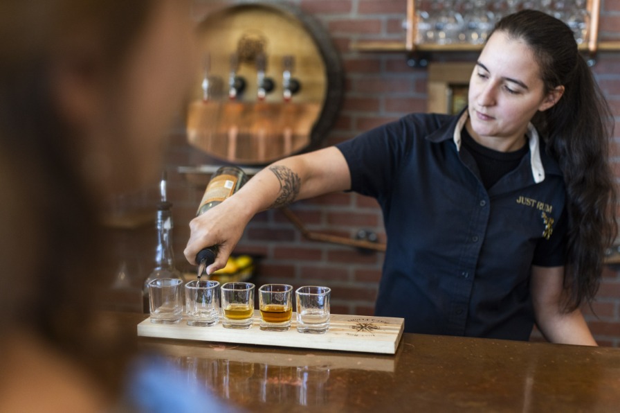 Bartender pours rum into a flight of shot glasses