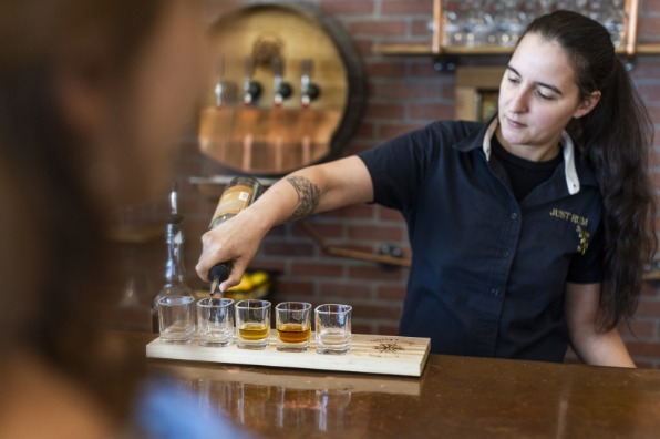 Bartender pours rum into a flight of shot glasses