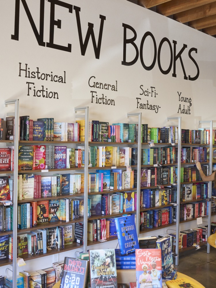 Wall of books reads "New Books" with genres listed below