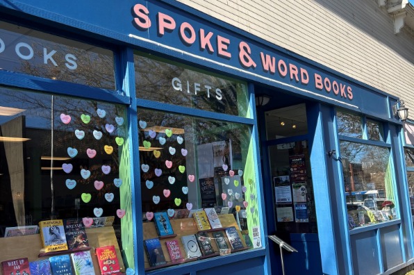 Blue storefront of bookshop with books on display in the front windows. 