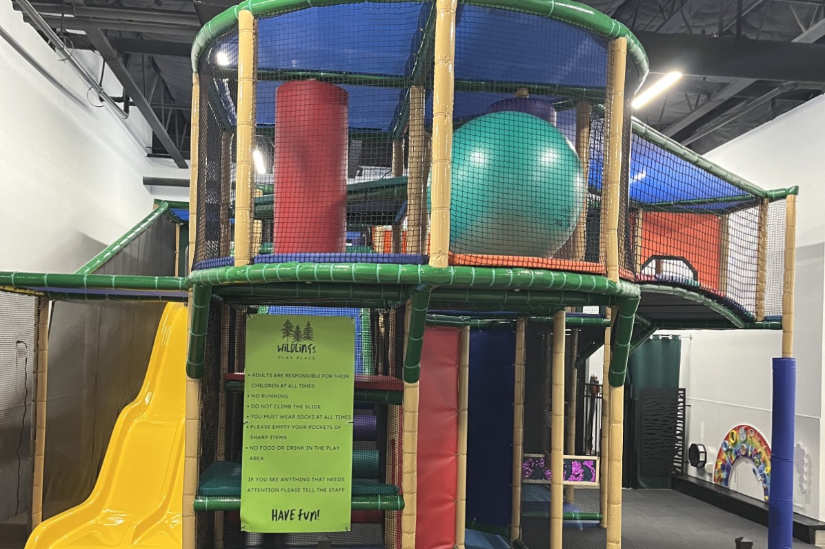 Brightly colored two story indoor play structure at Wildlings Play Place features a double slide. 