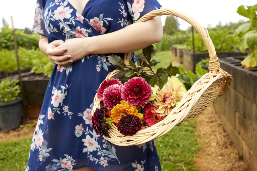 Person wearing a dress holds a basket of flowers
