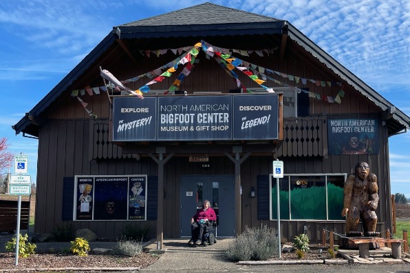 A visitor is outside of a brown building with blue sky above.