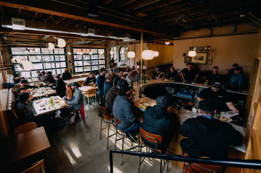 A group of customers sit around a curved cement bar