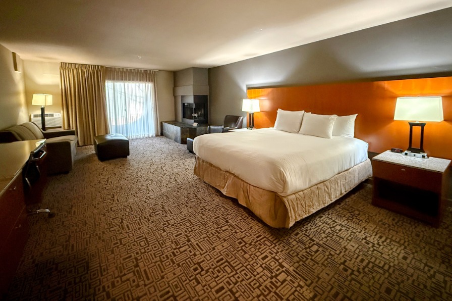 A hotel room with a white king size bed and a fireplace in the corner.