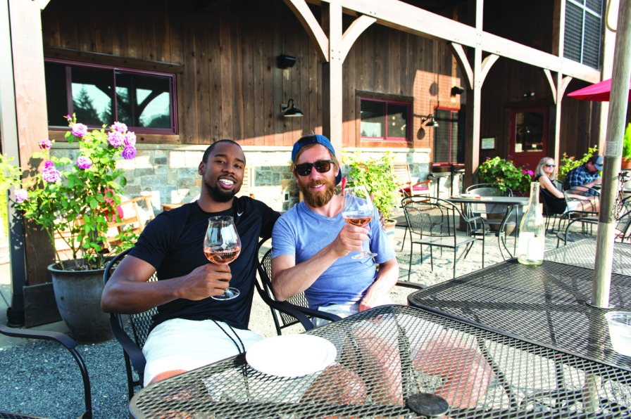 Two friends on a patio cheers with glasses of rose
