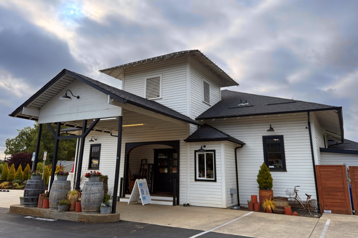 A white building with black roof against a cloudy sky