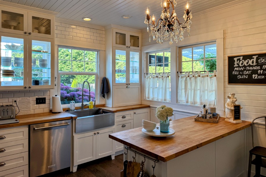A kitchen with white cabinets and wood counters