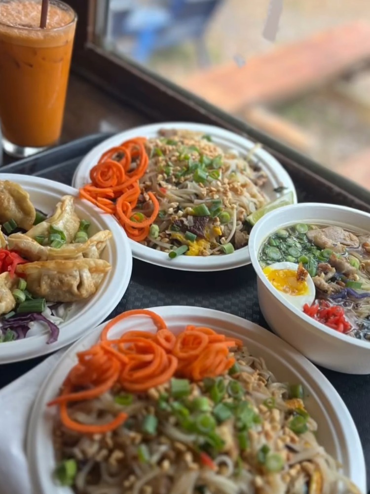 Two plates of fried rice, a bowl of ramen and a side of potstickers and thai iced tea