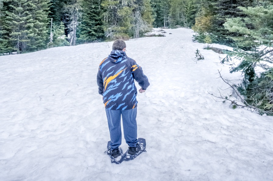 Snowshoeing is a wonderful way to get outside in the winter. A hiker with snowshoes on with white snow all around.