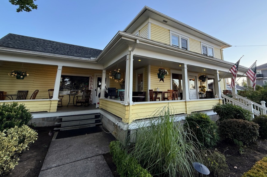 A yellow house with a wrap around porch