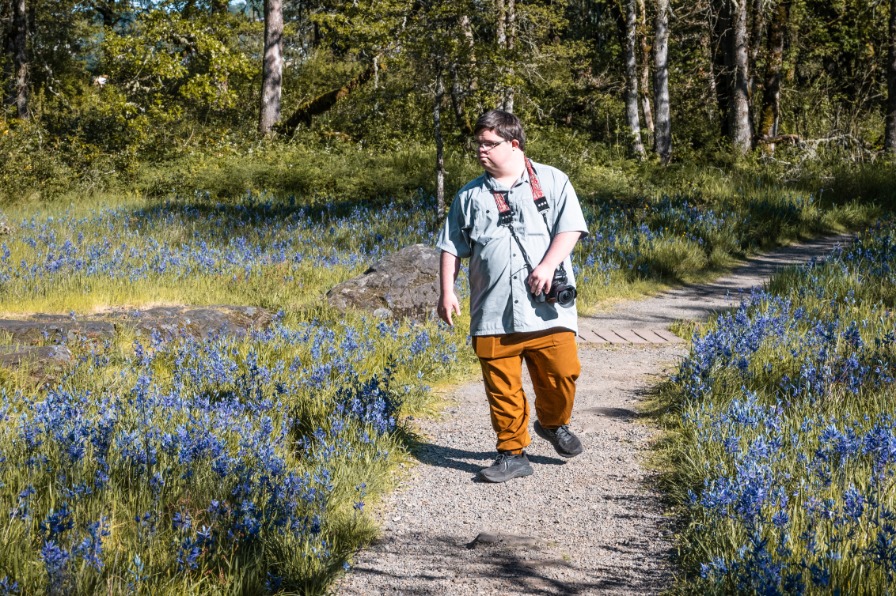 A hiker walks through fields of flowers