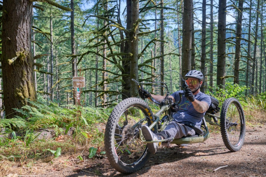 Adaptive mountain biking the Molalla River Recreation Cooridor A mountain biker on an adaptive mountain bike travels a dirt trail surrounded by green trees