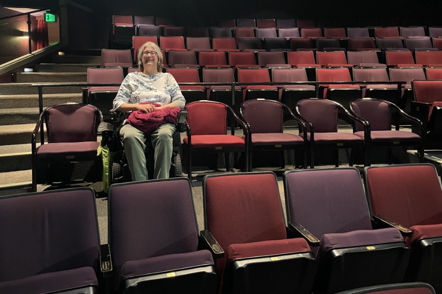A person in a wheel chair sits in a theater