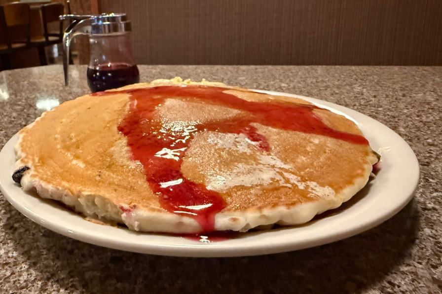 The huckleberry pancakes at the Huckleberry Inn. A stack of brown pancakes covered in purple huckleberry syrup