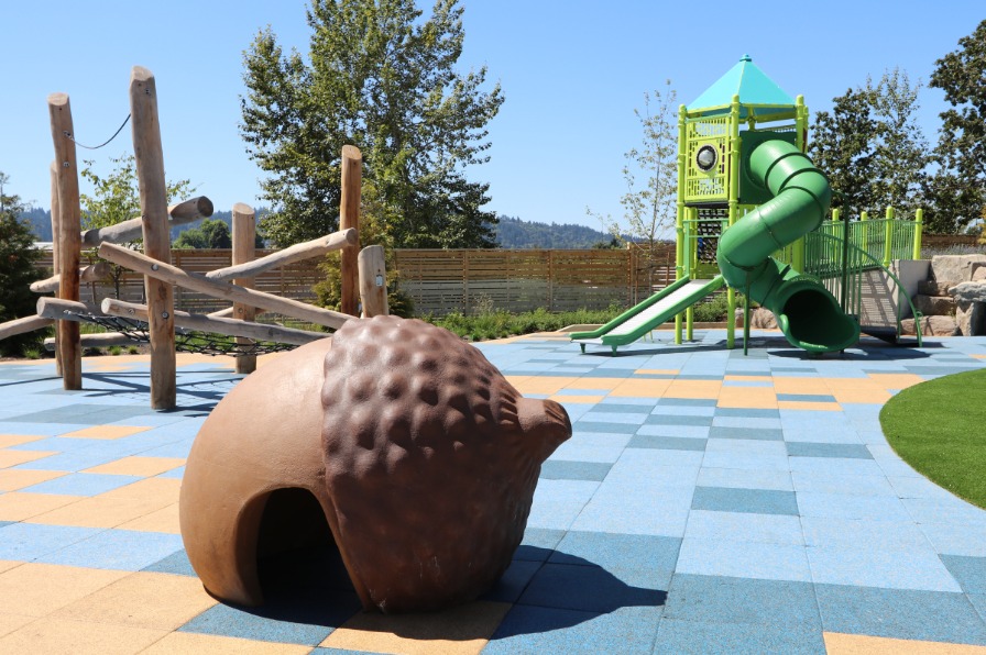 A playground with a wood walking area and a two story slide