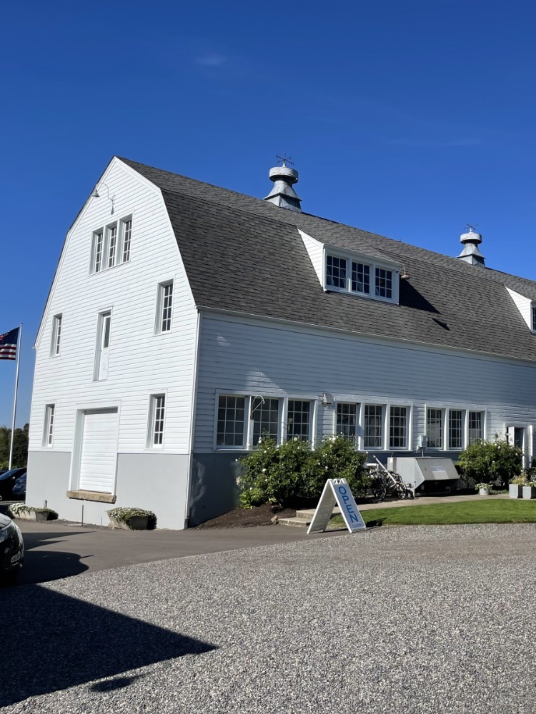 A large white barn stands against blue sky.