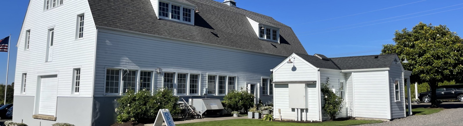 A large white barn stands against blue sky.
