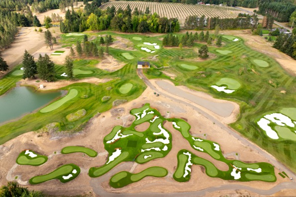 Aerial view of a golf course featuring lush green fairways, sand traps, and a pond, surrounded by trees and farmland. Ideal for outdoor recreation.