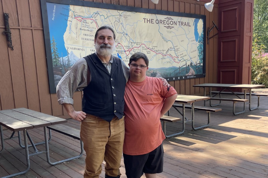 Two people stand next to a map of the Oregon Trail