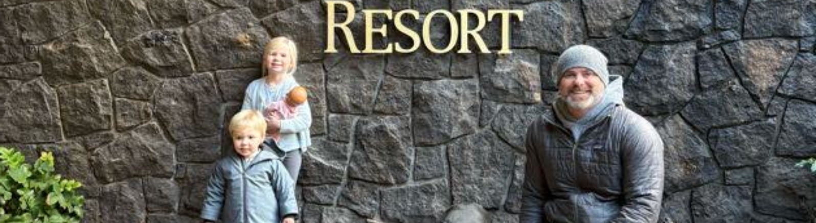Three visitors pose with a resort sign