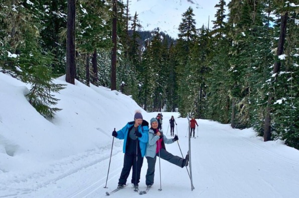 Cross country skiiers pose for the camera one a trail with Mt Hood in the background