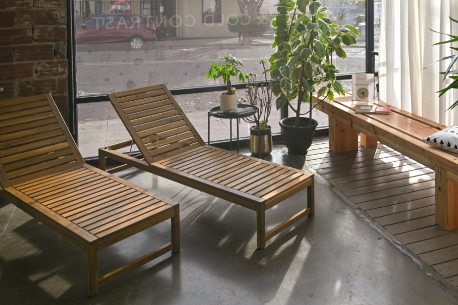 Two wooden chairs sit next to plants