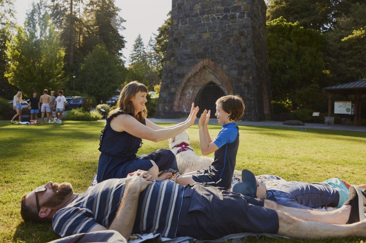 A family of four and their dog rests on a vibrant green lawn.