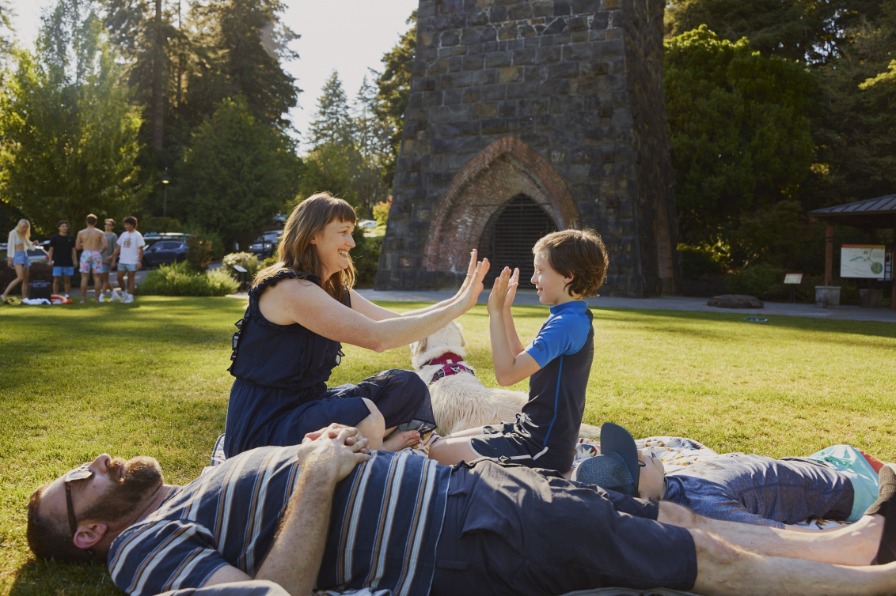 A family of four and their dog rests on a vibrant green lawn.