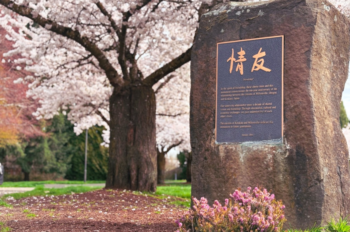 Landmark with Japanese symbols with trees covered in blossoms in background