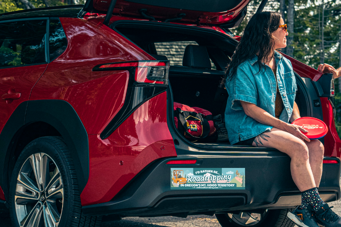A person sits on the tailgate of a red car