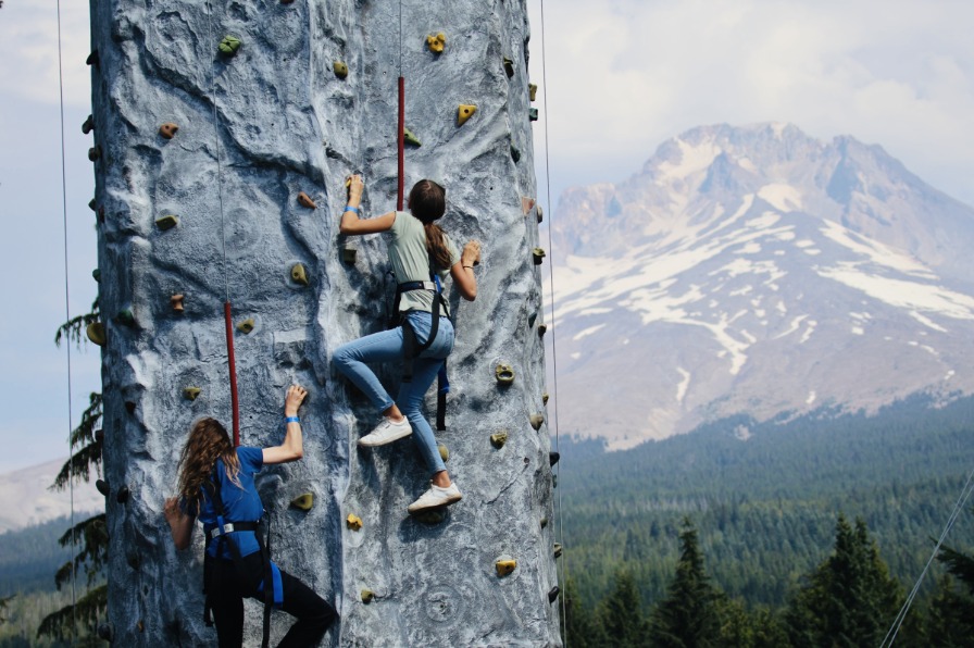 Mt. Hood Skibowl Summer Adventure Park A person climbs a fake rock wall with Mt. Hood in the background