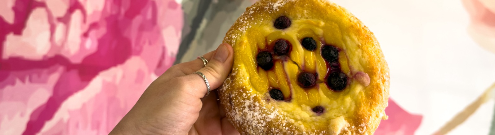 Hand holding up a pastry against floral wallpaper