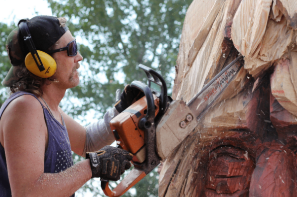 An artist caves a large peice of wood with a chainsaw at the Sandy Invitational Chainsaw Carving & Forest Festival