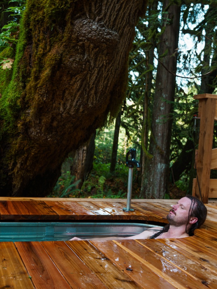 A vacationer relaxes in a cold plunge in the forest