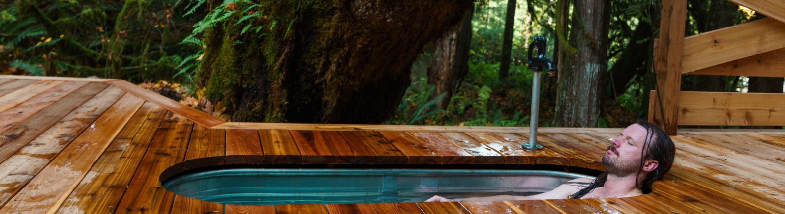 A vacationer relaxes in a cold plunge in the forest